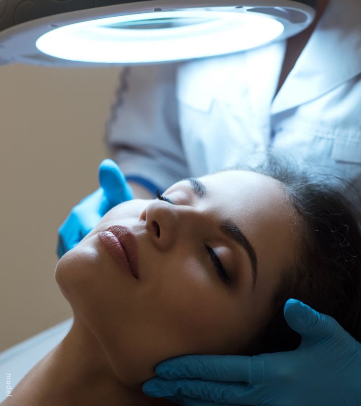 Woman's with eyes closed, her skin being looked at under light