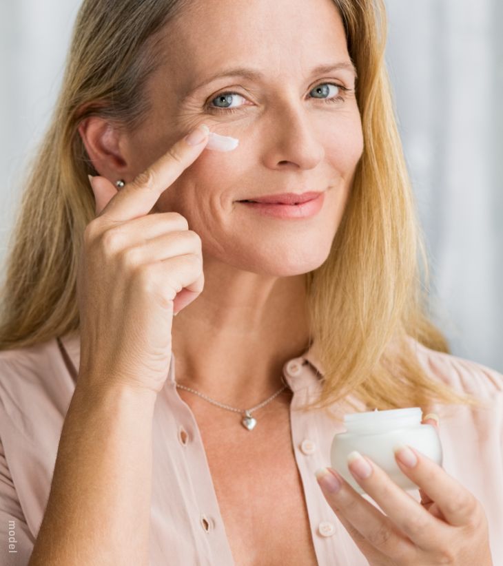 Woman applying skin moisturizer
